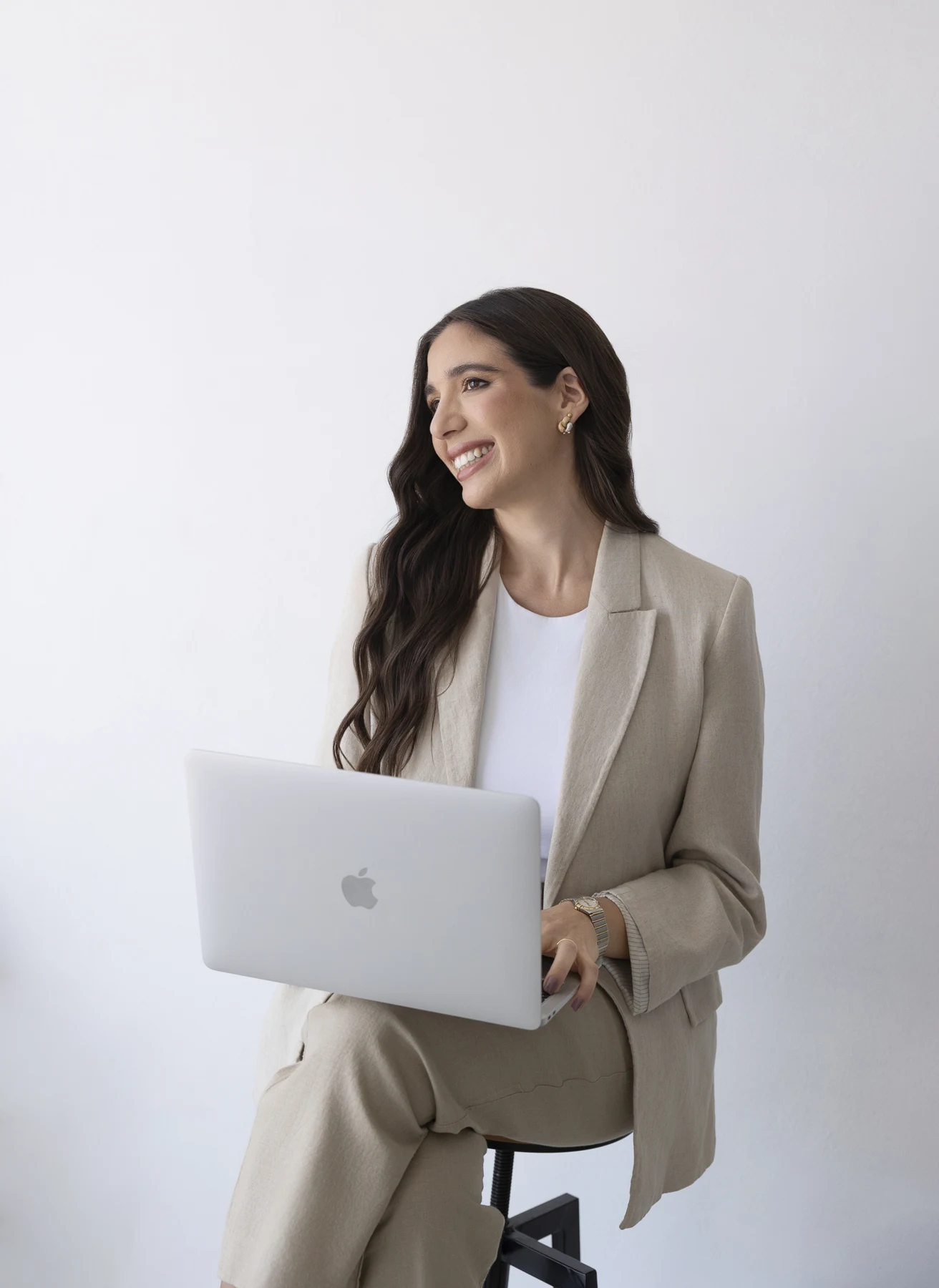 Jazmin Arias con una notebook, vestida con un traje beige